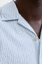 Neck detail image of a model wearing the Milo seersucker resort shirt in light blue, by brand Jack&jones
