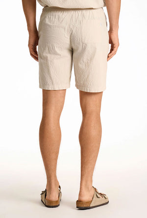 Back image of a model wearing the Seersucker shorts in beige, by brand Lindbergh