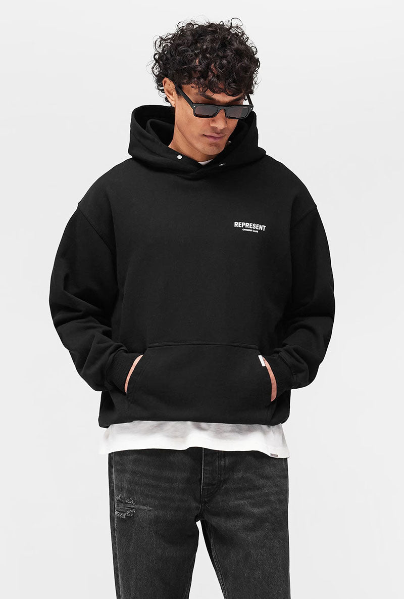 Front image of a model wearing Owners club hoodie in black, by brand Represent
