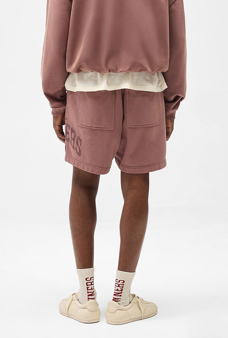 Back image of a model wearing Owners club script mesh shorts in brown, by brand Represent