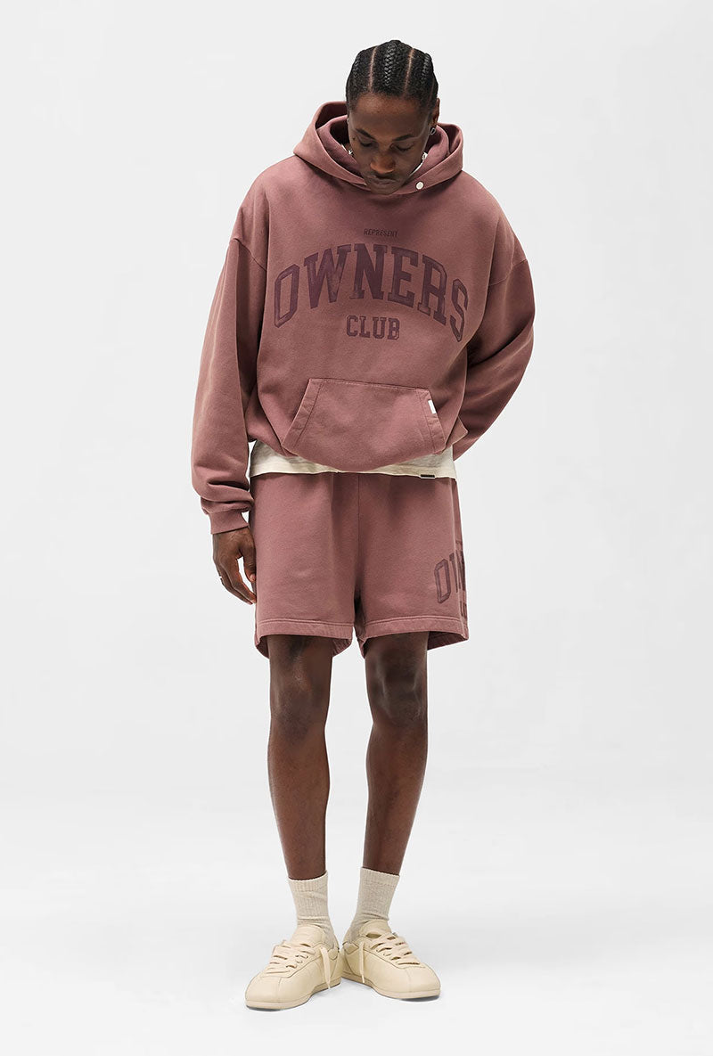 Front image of a model wearing Owners club script mesh shorts in brown, by brand Represent
