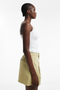 Front detail image of a model wearing the Eva a line shorts in sage, by brand Top shop