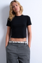 Front image of a model wearing the Everyday crop top in black, by brand Top shop