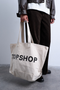 Front image of a model wearing the Ivy tote bag in white, by brand Top shop