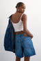 Back image of a model wearing the Vigga denim shorts in denim, by brand Top shop