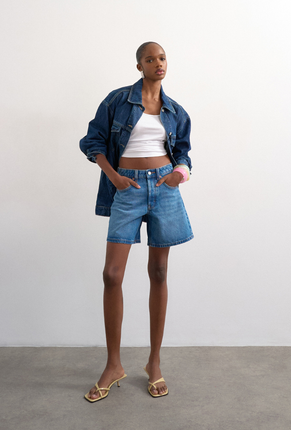 Front image of a model wearing Vigga denim shorts in denim, by brand Top shop