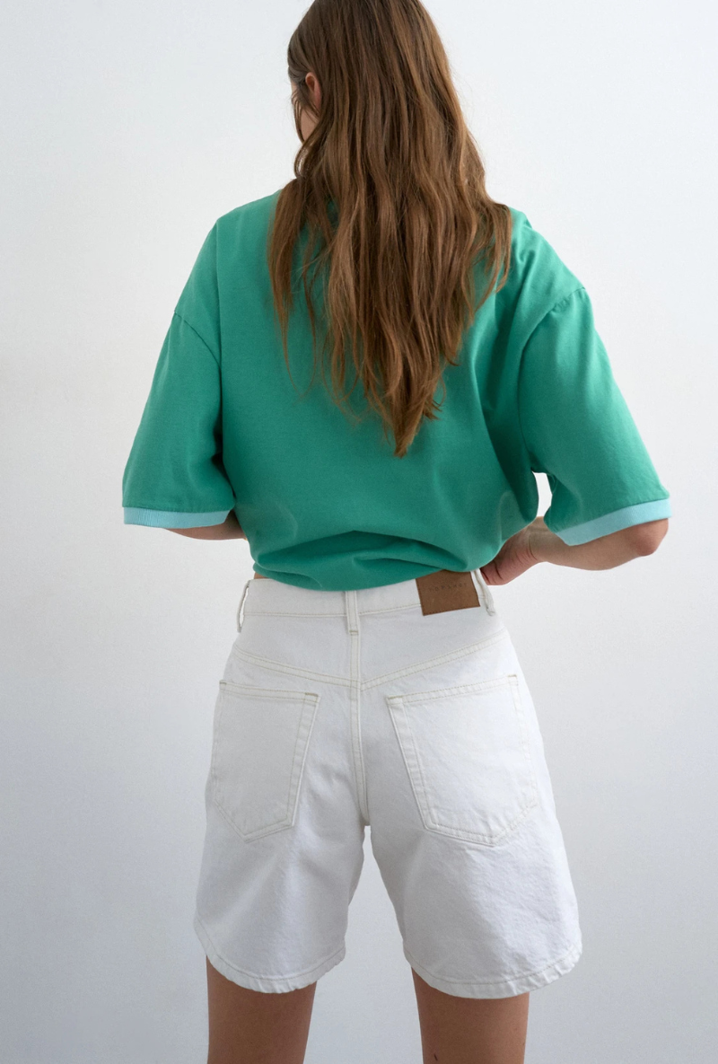 Back image of a model wearing Vigga high rise white denim shorts in white, by brand Top shop