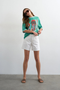 Front image of a model wearing Vigga high rise white denim shorts in white, by brand Top shop
