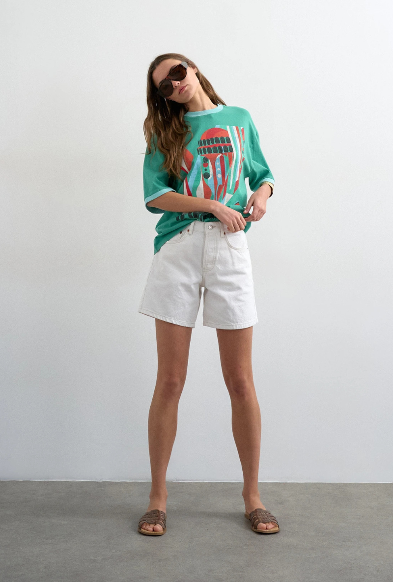 Front image of a model wearing Vigga high rise white denim shorts in white, by brand Top shop