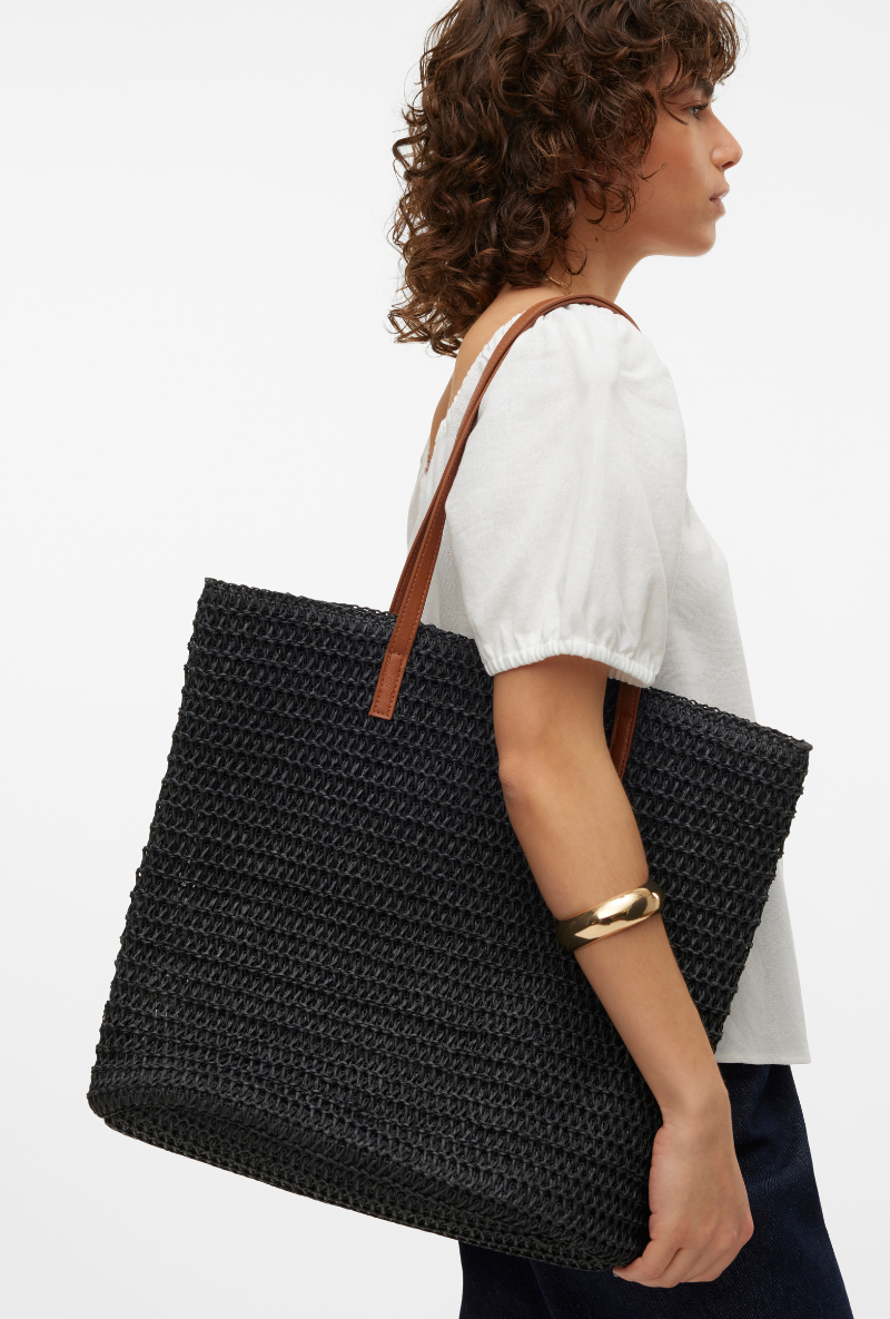 Side image of a model wearing Vero moda sisso beach bag in black, by brand Vero moda