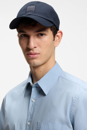 Front image of a model wearing the Derrel cap in navy, by brand Boss