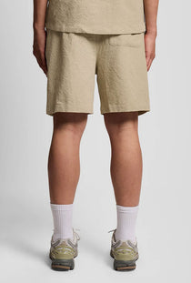 Back image of a model wearing the Crinkle resort shorts in stone, by brand Lyle and scott