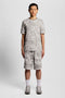 Front image of a model wearing the Industrial print sweat shorts in grey, by brand Lyle and scott