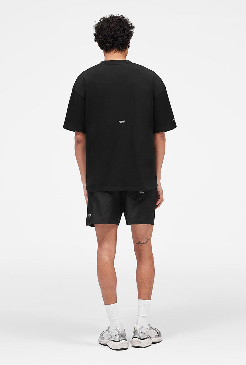 Back image of a model wearing Micro owners club swimshorts in black, by brand Represent