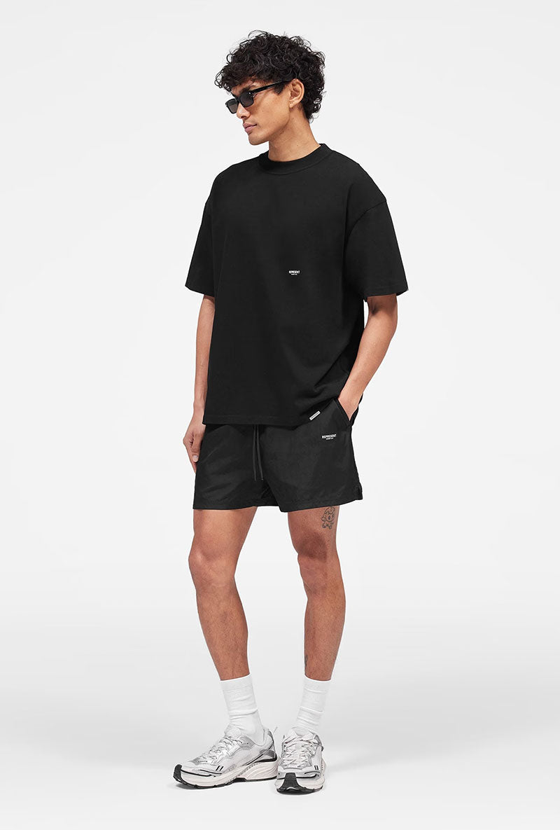 Front image of a model wearing Micro owners club swimshorts in black, by brand Represent