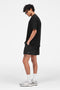 Front image of a model wearing the Micro owners club swimshorts in black, by brand Represent