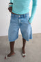 Front image of a model wearing the Joa denim barrel jort in denim, by brand Top shop