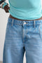 Front image of a model wearing the Joa denim barrel jort in denim, by brand Top shop