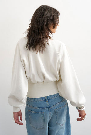 Back image of a model wearing the Rega cinch waist sweatshirt in off white, by brand Top shop
