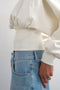 Front image of a model wearing the Rega cinch waist sweatshirt in off white, by brand Top shop