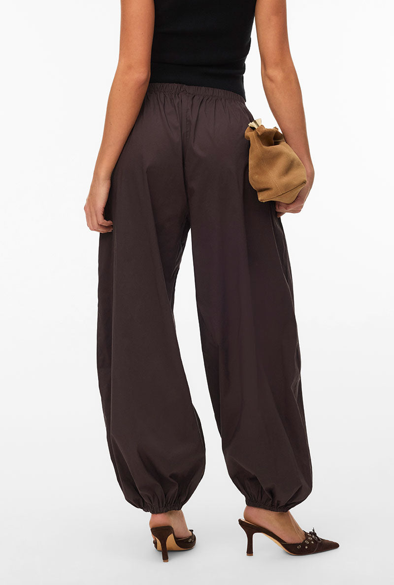 Back image of a model wearing Lotus balloon trousers in chocolate, by brand Vero moda